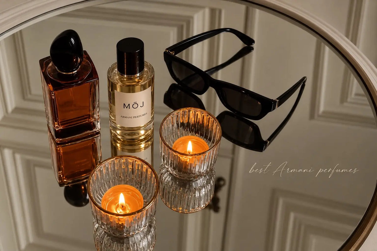 MOJ Armani perfume bottle with a black cap beside an amber Armani Stronger With You bottle, black sunglasses and two lit tealight candles on a round mirrored tray