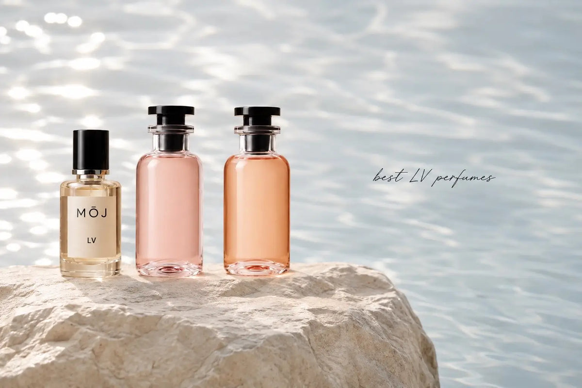 MOJ Louis Vuitton inspired perfume bottle beside two pink and peach glass perfume bottles on a pale rock above sunlit water